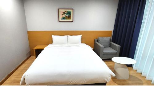 a bedroom with a white bed and a chair at Kwangsu Hotel Haeundae in Busan