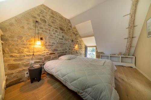 une chambre avec un grand lit et un mur en pierre dans l'établissement chaumière typique bretonne, à Carnac