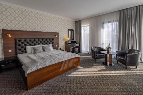 a hotel room with a bed and a desk and chairs at Hotel Castello & Thermal Spa Siklós in Siklós
