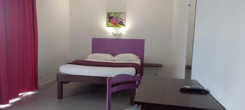 a small bedroom with a bed and a table at Hôtel Ballahou in Kourou