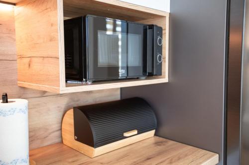 a microwave oven sitting inside of a wooden cabinet at Hron River Apartment in Brezno