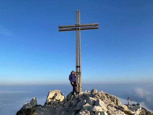 a man standing on top of a cross on a mountain at Chalet Schlossberg Weißhorn in Nova Ponente