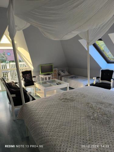 a bedroom with a bed and two chairs and a tv at Agroturystyka santa monica in Morzyczyn