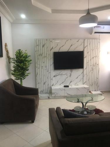 salon z kanapą, stołem i telewizorem w obiekcie Unity Royal Apartment w mieście Lagos