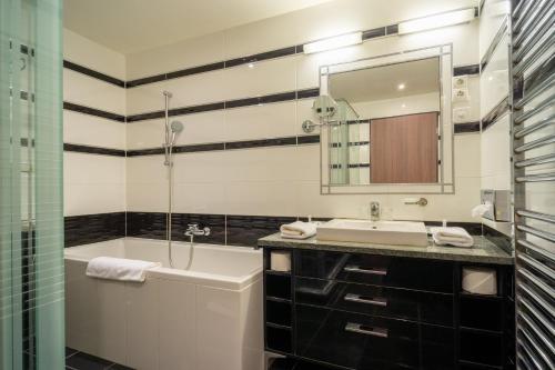 a bathroom with a sink and a tub and a mirror at Hotel Castello & Thermal Spa Siklós in Siklós