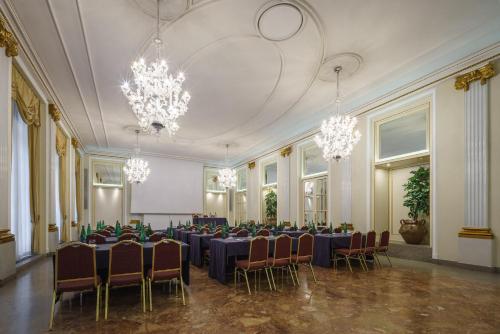 a room with tables and chairs and chandeliers at Eurostars Hotel Excelsior in Naples
