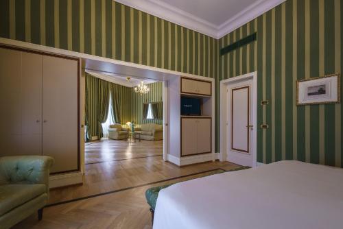 a bedroom with green striped walls and a bed and a living room at Eurostars Hotel Excelsior in Naples