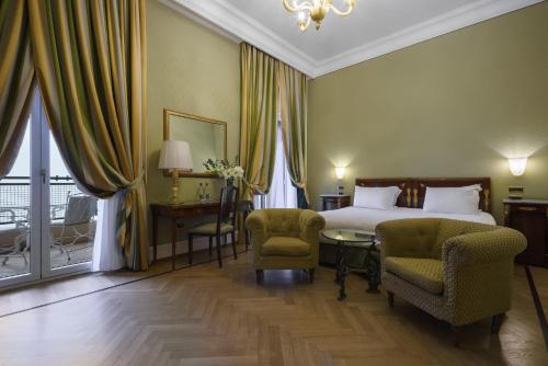 a bedroom with a bed and two chairs and a table at Eurostars Hotel Excelsior in Naples