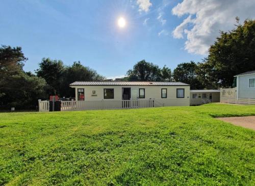 a house on a grassy field with a building at Sandy Toes Hoburne Devon Bay Holiday Park. in Paignton