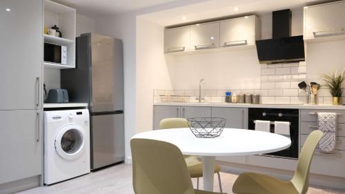 a kitchen with a white table and a laundry room at Lovely 2 Bed Apartment w Garden near Northampton in Earls Barton
