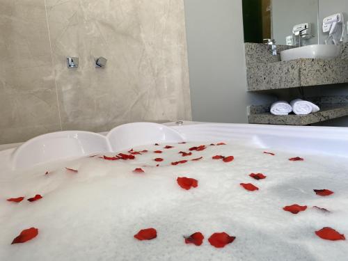 a bathroom with red roses on the floor of a bath tub at Pousada Maria Monteiro Tiradentes in Tiradentes