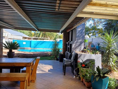 a patio with a wooden pergola and a table and chairs at Orchard Guesthouse in Bloemfontein