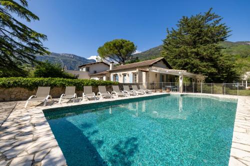 une piscine avec des chaises et une maison dans l'établissement Spacious villa in Tourrettes-sur-Loup with Private Lake access Sleep 16, à Tourrettes-sur-Loup