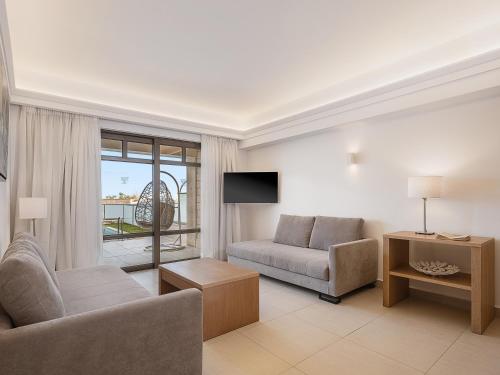 a living room with a couch and a chair at Porto Platanias Beach Resort & Spa in Plataniás