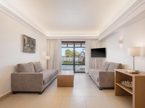 a living room with a couch and a tv at Porto Platanias Beach Resort & Spa in Plataniás