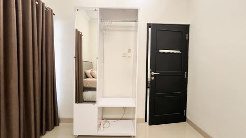 La salle de bains est pourvue d'un miroir et d'une porte noire. dans l'établissement Moona Homestay Jogja, à Gondowulung