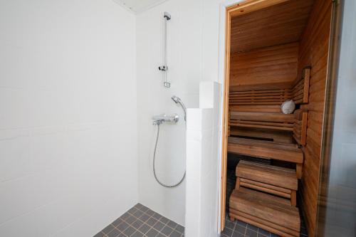 a bathroom with a shower with a wooden wall at Holiday Villa Kallan Pore in Kalajoki