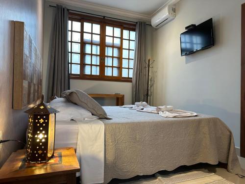 a bedroom with a bed and a tv on the wall at Pousada Maria Monteiro Tiradentes in Tiradentes