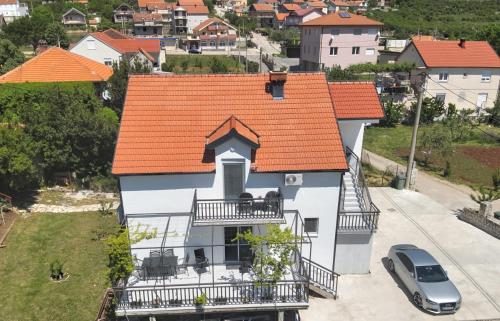 an orange roofed house with a balcony and a car at Apartments Honey House in Trebinje