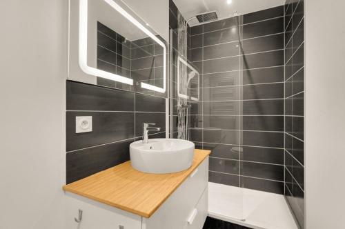 La salle de bains est pourvue d'un lavabo blanc et de carrelage noir. dans l'établissement La Petite Toulousaine - T2 proche gare, à Toulouse