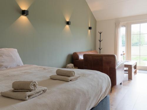 Un dormitorio con una cama y una silla y una ventana. en Hof van Eese - De Velduil, en Eesveen