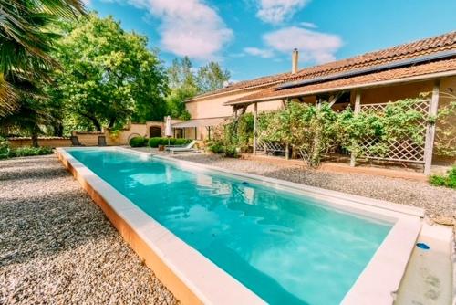 a swimming pool in front of a house at Domaine de la Hargue in Manciet