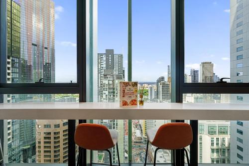 メルボルンにあるElegant High Rise 2 Bed Apt near Melb CBD RMITの窓際の椅子2脚付きテーブル