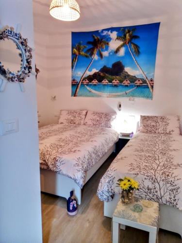 two beds in a room with palm trees at La perla di Maria in Grado