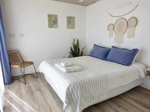 a bedroom with a bed with blue pillows and a chair at Paso Calmo Cabañas in Villa General Belgrano