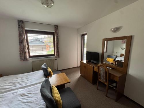 a bedroom with a bed and a desk and a mirror at Guest House Bakhus in Žerjavka