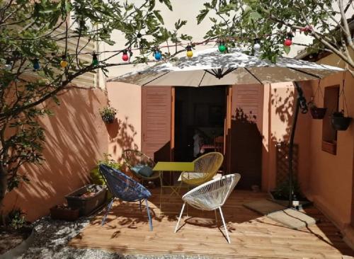 eine Terrasse mit Stühlen, einem Tisch und einem Sonnenschirm in der Unterkunft La Colombe in Beblenheim