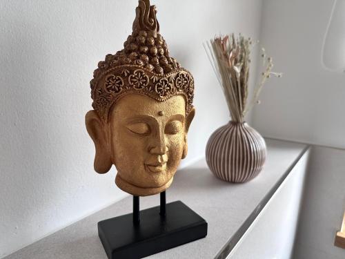 a statue of a head on a table next to a vase at Ferienwohnung Schneeflock in Birkfeld