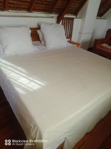 a large white bed with white sheets and pillows at My Little House in Mandriankeniheny