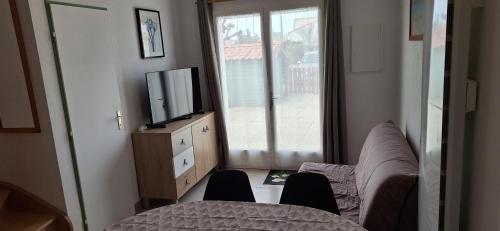 un salon avec un canapé et une télévision dans l'établissement Domaine, à Saint-Hilaire-de-Riez