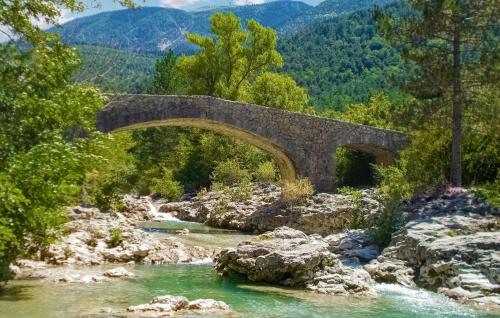 a stone bridge over a river in the mountains at Maison Vue Panoramique in Plaisians