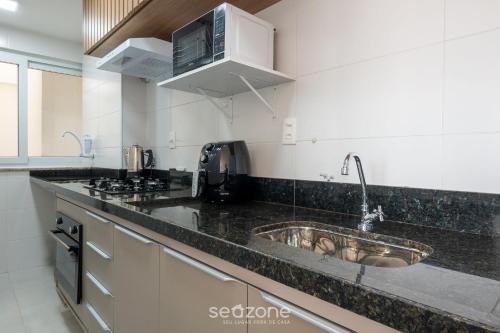 a kitchen with a sink and a microwave at Apartamentos em Condomínio com Piscina e Academia - AGA in Camaçari