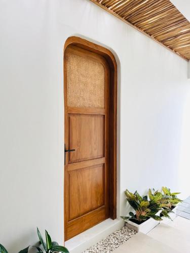 a wooden door in a white wall with plants at The Bora Villas in Ngaglik
