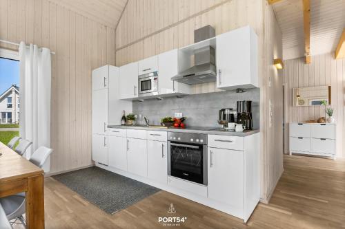 une cuisine avec des armoires blanches et une cuisinière dans l'établissement Ferienhaus Hygge Hus Olpenitz, à Olpenitz