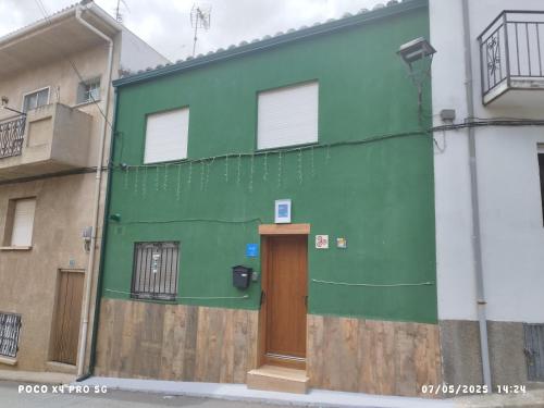 a green building with a wooden door on a street at CASA GORDON in Navaluenga