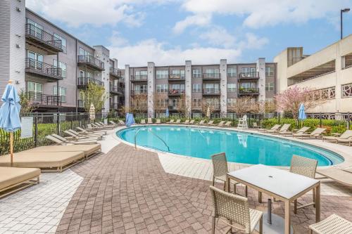 una piscina con sillas y mesas frente a un edificio en Luxury Downtown Crown Apartment, en Gaithersburg