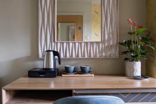 a coffee maker and two cups on a wooden table at Hanley House in Tenbury