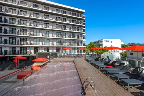 budynek z krzesłami i parasolami przy basenie w obiekcie Hotel Vibra District - Adults Only w mieście San Antonio