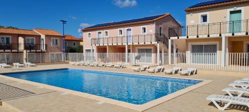 a swimming pool with lounge chairs and a building at Appart'hotel Résidence La Provence in Istres