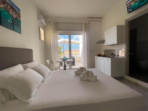 a white bedroom with a large white bed and a kitchen at Rest House The Village in Nardò