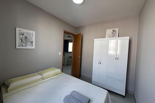 a white bedroom with a bed and a cabinet at Apartamento a 15min do Aeroporto de Confins in Lagoa Santa
