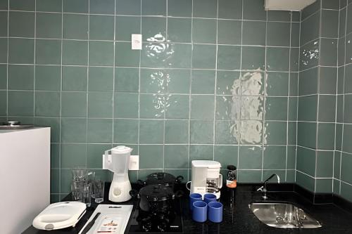 a kitchen with green tiled walls and a counter top at Apartamento a 15min do Aeroporto de Confins in Lagoa Santa