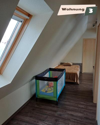 a attic room with a bed and a crate at Ferienwohnung Zum Böhmischen Bürgergarten in Radebeul