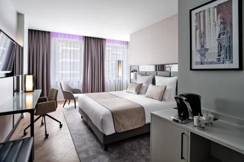 a hotel room with a bed and a desk at Leonardo Royal Hotel Warsaw in Warsaw