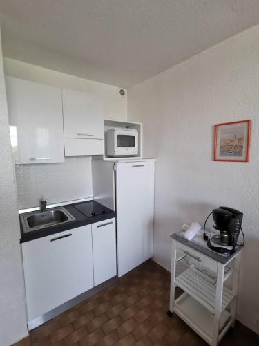 une petite cuisine avec un évier et un micro-ondes dans l'établissement Studio Héliopolis L48 - 2 personnes, au Cap d'Agde