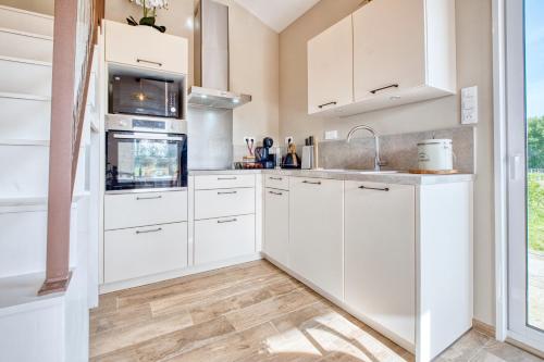 a kitchen with white cabinets and wood floors at Le Refuge des Vignes in Lamonzie-Saint-Martin